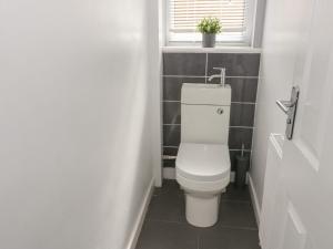 a bathroom with a toilet and a window with a plant at Bay View Bungalow Benllech, 5 Min Walk from Beach in Benllech