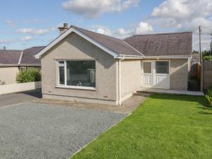 une maison en briques avec une pelouse devant elle dans l'établissement Bay View Bungalow Benllech, 5 Min Walk from Beach, à Benllech