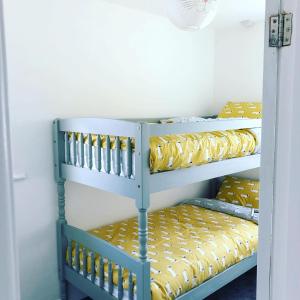 two bunk beds in a room with yellow pillows at Bay View Bungalow Benllech, 5 Min Walk from Beach in Benllech