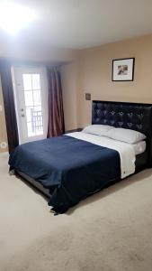 a bedroom with a large bed with a blue blanket at Cozy jets empire in Brampton