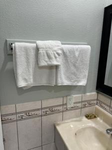 a bathroom with white towels hanging on a wall at La Cienega Inn Motel in Los Angeles