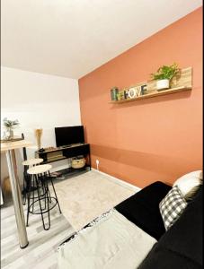 a living room with an orange wall with a desk at Studio centre-ville Petite Venise in Colmar