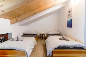 two beds in a room with white walls and wooden ceilings at Casanova Apartments - Viewpoint in Vrsar