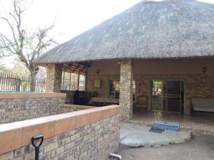 - un petit bâtiment en briques avec un toit de chaume dans l'établissement Collin's Rest, à Marloth Park