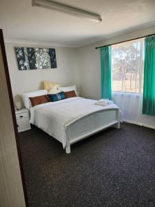 a bedroom with a bed with green curtains and a window at Country Retreat The Blue Cottage in Gingin