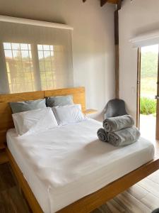 a bedroom with a white bed with a chair at Finca hotel la fortuna in San Pedro