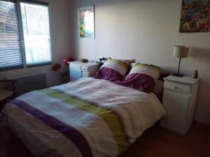 een slaapkamer met een bed met een kleurrijke sprei bij La campagne au bord de la mer, chambre chez l'habitant in Champeaux