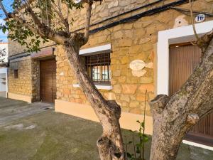 a tree in front of a stone building at Casa Rural Claudia in Puigmoreno