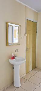 a bathroom with a white sink and a mirror at Kapowlito Real Estate Casa #1 Mon Plaisirweg in Paramaribo