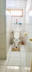 a white bathroom with a toilet and a window at Kapowlito Real Estate Casa #1 Mon Plaisirweg in Paramaribo