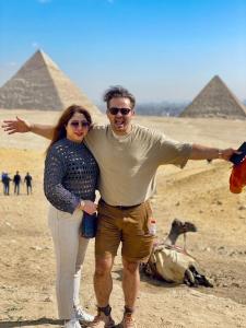 a man and a woman standing in front of pyramids at four pyramids Guest house in Cairo