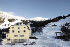 um grande edifício amarelo na neve com carros estacionados em Slope-Side Fun Ski-In Ski-Out Retreat for 3 em Åre