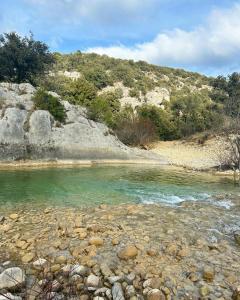 um corpo de água com pedras e uma montanha em Maison piscine & spa Vallon Pont d'Arc em Vallon-Pont-dʼArc