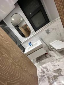 a bathroom with a sink and a toilet and a mirror at Luxury Hotel apartment one bedroom - Aeon Towers for families or individuals in Sheikh Zayed