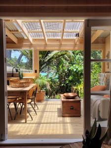 a room with a patio with a table and a glass door at The Bay Cottage - Located Directly Across the Road from 2 Swimming Beaches in Great Barrier Island