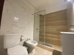 a white bathroom with a toilet and a shower at Ubatuba Lofts Mar Azul - depto 2 hab in Mar Azul
