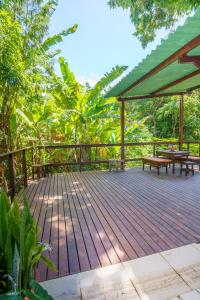 une terrasse en bois avec des bancs et un parasol vert dans l'établissement Casa da Marcia, à Fernando de Noronha