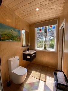 a bathroom with a toilet and a sink and a window at The Bay Cottage - Located Directly Across the Road from 2 Swimming Beaches in Great Barrier Island