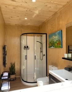 a bathroom with a shower and a toilet and a sink at The Bay Cottage - Located Directly Across the Road from 2 Swimming Beaches in Great Barrier Island +17 photos