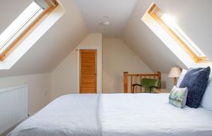 a bedroom with a large white bed with skylights at Solas Alainn Chalet in Portree