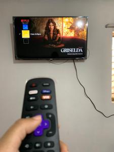 a person holding a remote control in front of a television at Apartamento Casa Antigua in Santa Ana