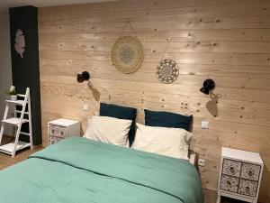 - une chambre avec un lit et un mur en bois dans l'établissement Maison d hôtes SPA Pivoine et Colibri, à Domfessel
