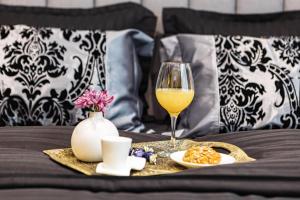 a glass of wine and a plate of food on a bed at LUXIMO ROOM in Veliko Tŭrnovo