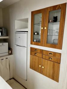a kitchen with a white refrigerator and wooden cabinets at La Maison Plume, Appart Boutique in Saint-Rémy-de-Provence