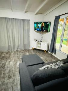 a living room with a couch and a tv at Cabaña en Villa del Deportista Villa Shalom in Necochea