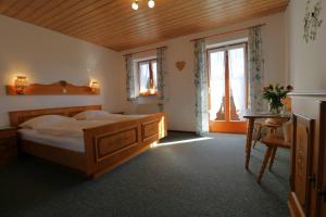 Schlafzimmer mit einem Bett, einem Tisch und Fenstern in der Unterkunft Gästehaus Hillebrand in Bischofswiesen