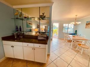 a kitchen with a sink and a dining room with a table at Beach Condo with Game Room Steps To Beach in Clearwater Beach