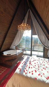 a bedroom with a bed with a chandelier and a tub at Chalés Capivari Diamante in Campos do Jordão
