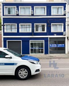 a white car parked in front of a blue building at Hotel Lara 10 Curitiba in Curitiba
