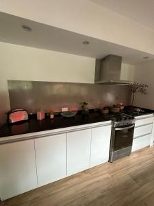 a kitchen with white cabinets and a stove at Hospedaje posada en Ezeiza in Ezeiza