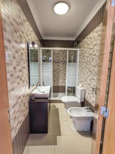 een badkamer met 2 toiletten, een wastafel en een bad bij Villa Algarve- Townhouse in Farm Village, Albufeira in Albufeira
