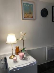 a table with a lamp and flowers and a clock at Studio house near paris in Épinay-sur-Seine