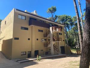 a building with a staircase next to a tree at Ubatuba Lofts Mar Azul - depto 2 hab in Mar Azul