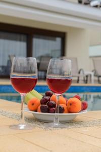 dos copas de vino sentadas en una mesa con fruta en Villas Hanioti, en Chaniotis