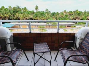 a balcony with chairs and a view of palm trees at Gran lençóis Flat tipo A piscina in Barreirinhas
