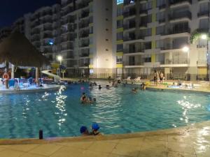 um grupo de pessoas em uma piscina à noite em apartamento en ricaurte, conjunto peñazul la aldea em Ricaurte