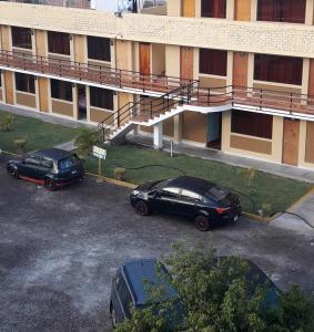 皮斯科的住宿－Hospedaje Huamani & Mi Casa，两辆汽车停在大楼前的停车场