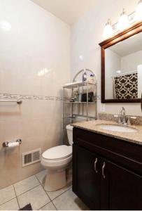 a bathroom with a toilet and a sink and a mirror at Quiet apt only 15 mins away from Midtown Manhattan in Jersey City