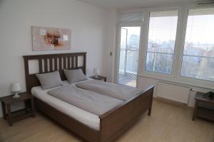 a bedroom with a bed with white sheets and windows at Sunny Apartment with amazing Terrace on the 13th floor near City Center in Bratislava