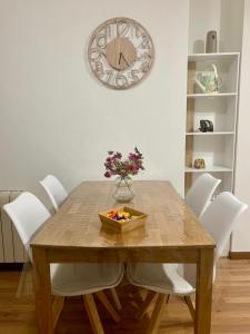 una mesa de comedor con un tazón de flores y un reloj en Plaza America Home, en Vigo