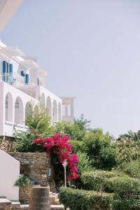 um grupo de edifícios brancos com flores e arbustos cor-de-rosa em Aneroussa Beach Hotel em Batsi