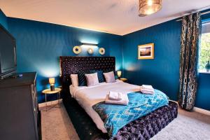 1 dormitorio con paredes azules y 1 cama con almohadas en The Chase, Luxury Hot Tub Retreat, Pets Welcomed en Dipton