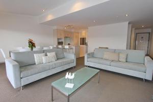 a living room with two couches and a table at Crow's Nest Apartments in Whitianga