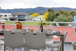 a table with chairs and a bottle of wine on a balcony at Crow's Nest Apartments in Whitianga