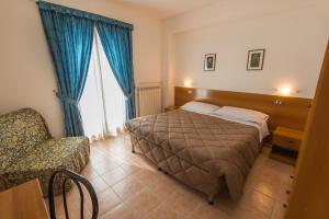 a hotel room with a bed and a chair at Albergo Della Corte in Pescasseroli