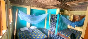 a room with two beds and a blue wall at Auberge chez M in Ganvié